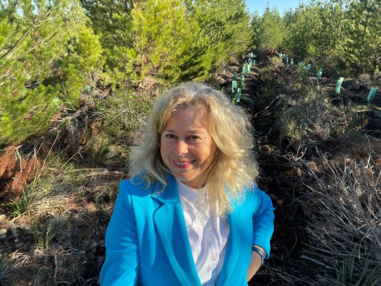 Dr. Sybille Buchwald-Werner in blue jacket standing in a forest with young trees in chile