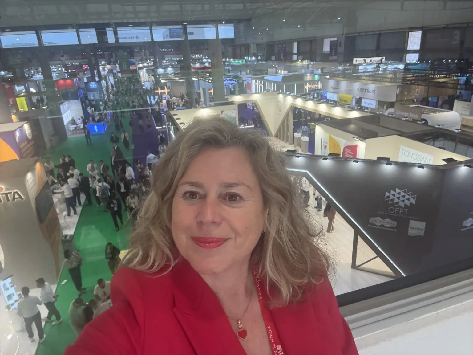 Woman in red at bustling trade show with exhibition booths